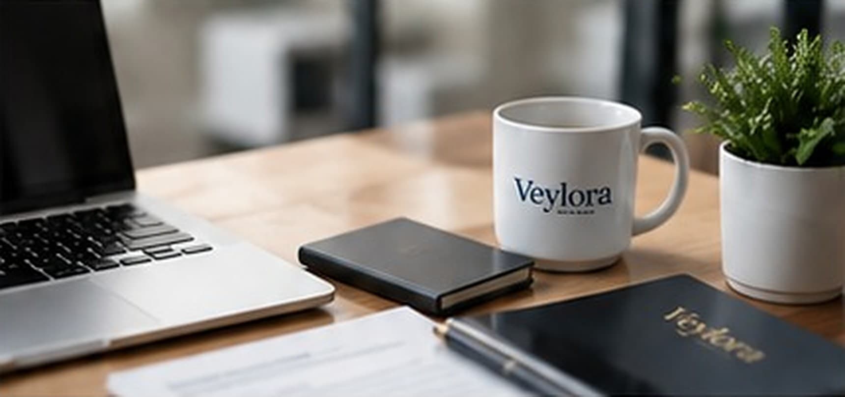 Laptop, notebook and a Veylora mug on a desk